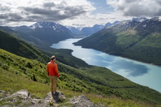 Mountaineer enjoys views of blue lake and mountains on Twin Peaks Trail, Eklutna Lake, Chugach