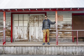 Young man standing on the porch of a former Gold Mine Independence Mine building in mountainous