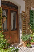 Garden flowers in pots by a wooden door to a idyllic residential house in a village, Fornalutx,