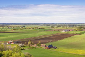 View of a cultivated plain landscape with farms and red barns a sunny spring day in th e