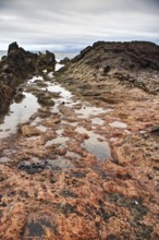 Close-up of rocky coastline with puddles, dramatic sky in background, Chargo Verde El Golfo
