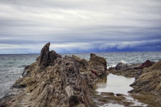 Rugged coastal landscape with rocks in the foreground and a cloudy sky over the sea, Chargo Verde