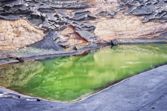 Green volcanic lake (Lago Verde) surrounded by dramatic rock formations and landscape reflections,