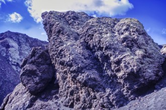 Impressive rock formation of volcanic rock rising against a blue sky, partial view of El Cuervo