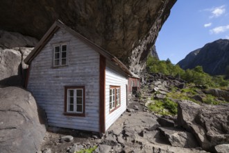 Historical wooden houses sheltered under a massive rock overhang. Summer, Helleren (Helleren),