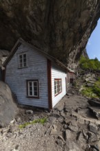 Historical wooden houses sheltered under a massive rock overhang. Summer, Helleren (Helleren),
