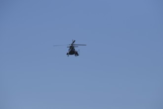 A helicopter can be seen from afar in the blue sky while it is working, Lemförde, Lower Saxony,