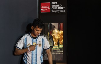A football fan poses for a photograph with the original FIFA World Cup 2026 Trophy during the