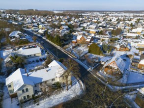 Inhabited area in snow with several houses along a road on a clear day, aerial view, Oelsburg,