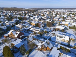 Residential district in winter under clear sky, with snow-covered roofs and roads, aerial view,