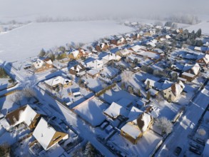 Snowy village with houses and roads next to a large snowy field, aerial view, Oelsburg, Ilsede,