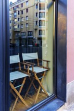 Two wooden chairs stand behind a shop window, Berlin, Germany
