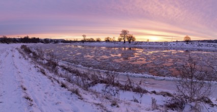 Panorama on a cold winter morning on the Elbe with floating ice floes, snow and dawn at sunrise,