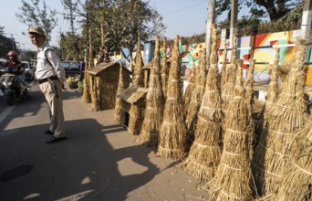 A police personnel stands as vendor display Meji (Bonfire) to sell near a road, as part of