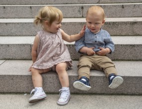 Act of friendship between two blonde children, boy and girl 1.5 years old in Ystad, Skåne County,