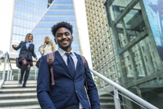 African american businessman smiling at camera and walking up stairs in a modern urban environment