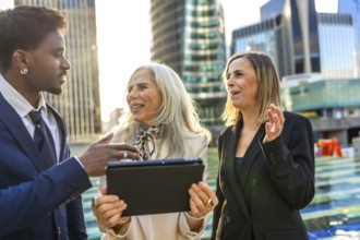 Diverse business team engaging in an informal outdoor meeting, discussing a project while looking