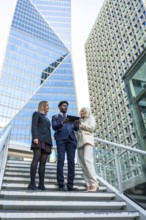 Diverse business team meeting on outdoor stairs in a downtown corporate district, collaborating