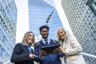 Diverse business people smiling and showing teamwork, standing outdoors in a corporate city