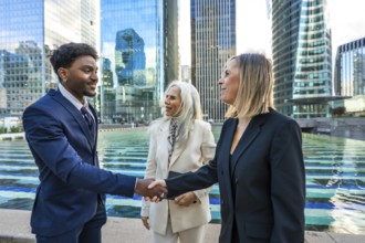 Diverse business people making a deal, shaking hands outdoors in a modern city corporate