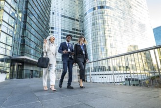 Diverse business professionals, including a senior woman, walking together on an urban walkway