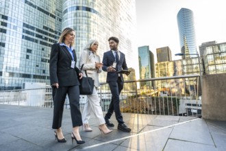 Three diverse business people walking outdoors on an elevated pedestrian area, engaged in