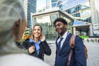 Diverse business professionals smiling and communicating while standing in a modern urban district,