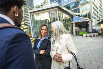 Group of multi ethnic business people engaged in an outdoor conversation with smiling women,
