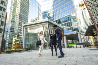 Diverse business professionals having a conversation while walking together through a modern urban