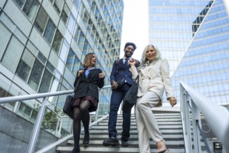 Diverse group of business professionals walking down outdoor stairs in a modern financial district,