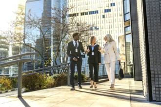 Three diverse business professionals, a woman, a man, and a senior woman, walking and actively