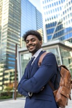 Young black businessman standing confidently in a modern urban environment, carrying a brown