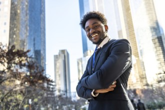 Young adult african american businessman standing with arms crossed. Smiling broadly at the camera.