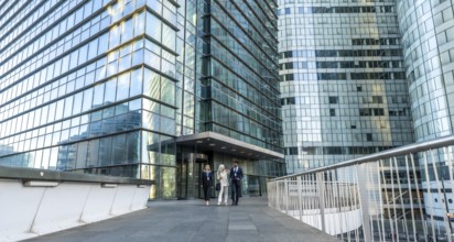 Business professionals walking together on an elevated pedestrian walkway, surrounded by