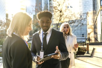 Business colleagues collaborating on an outdoor urban meeting, exchanging ideas while reviewing