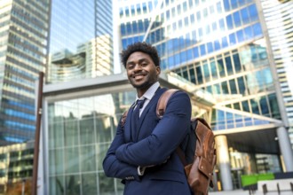 Young black businessman smiling. Wearing a suit and brown backpack. Confidently standing with arms
