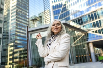 Senior businesswoman with gray hair and a formal blazer smiling confidently, standing outdoors