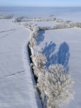 Snowy fields with a straight river surrounded by frosty trees under a blue sky, Fuhse river,