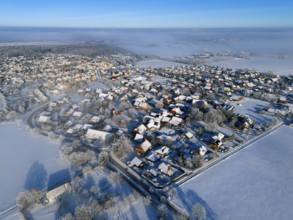 Snowy village under clear sky, sunlight reflected on white roofs and trees, aerial view, partly