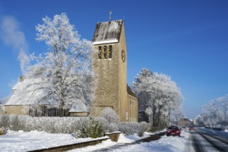 Village church with snow-covered trees against clear blue sky, car on the road, St. Mark's Church,