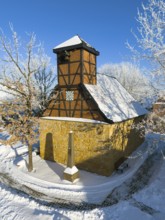 Snow-covered half-timbered church with clear structure and blue sky in cold surroundings, Old