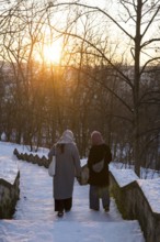 Two woman walk on snowy stairs with evening sun in Volkspark Friedrichshain on 07.01.2026