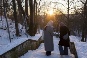 Two woman lean on a snowy staircase with evening sun in Volkspark Friedrichshain on 07.01.2026