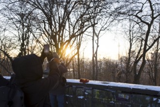 People take pictures of the Berlin TV Tower with their cell phones from Volkspark Friedrichshain on