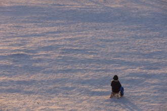 A child sits alone on a sled on Tempelhofer Feld in Berlin on 11.01.2026