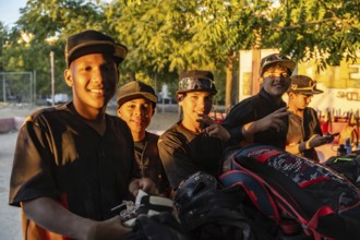 Young baseball players standing together after practice, smiling in jerseys and caps on a sunny