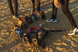 Baseball players gathering on a dusty field at sunset, discussing strategy while their bats,