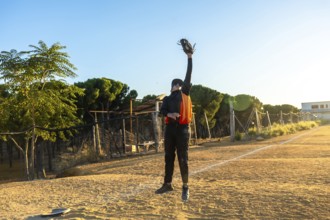 Baseball player in uniform leaps on a sunny field, arm outstretched with glove to snatch a fly ball