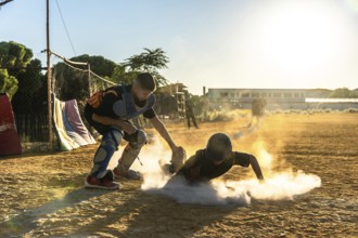 Young baseball player slides into base, sending up a cloud of dust as catcher waits on the dirt