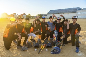 Diverse youth baseball team smiling and cheering on the field at golden hour, surrounded by bats,